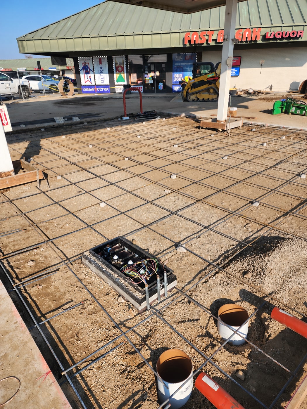 Dispenser sump, piping risers, and a rebar grid prepared beneath a station canopy