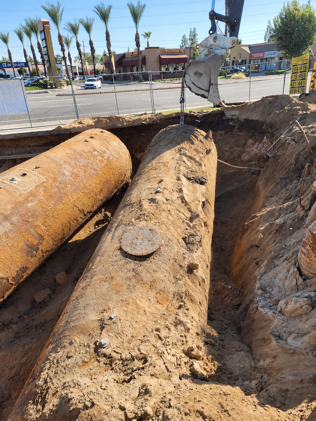 Excavator and lifting chain positioned above old underground fuel tanks
